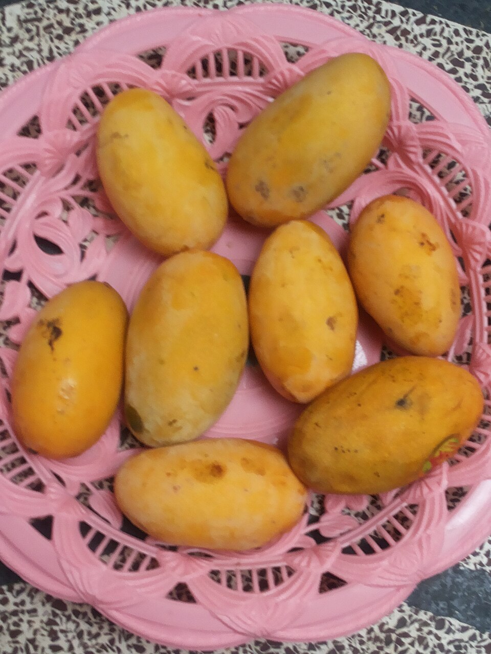 Elongated yellow Dasehri mangoes arranged in a pink basket
